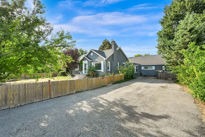 Gabled roofline, gray siding, white trim, and a gravel driveway