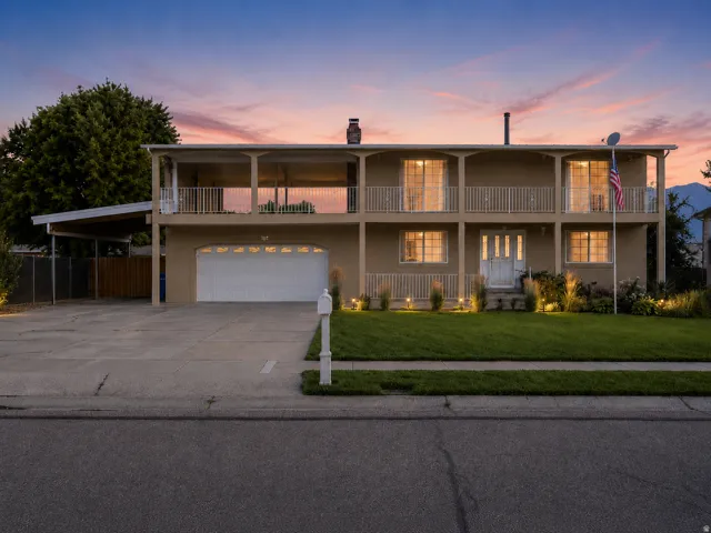 Two-story residence featuring a full-width upper balcony and a lower porch with white railings