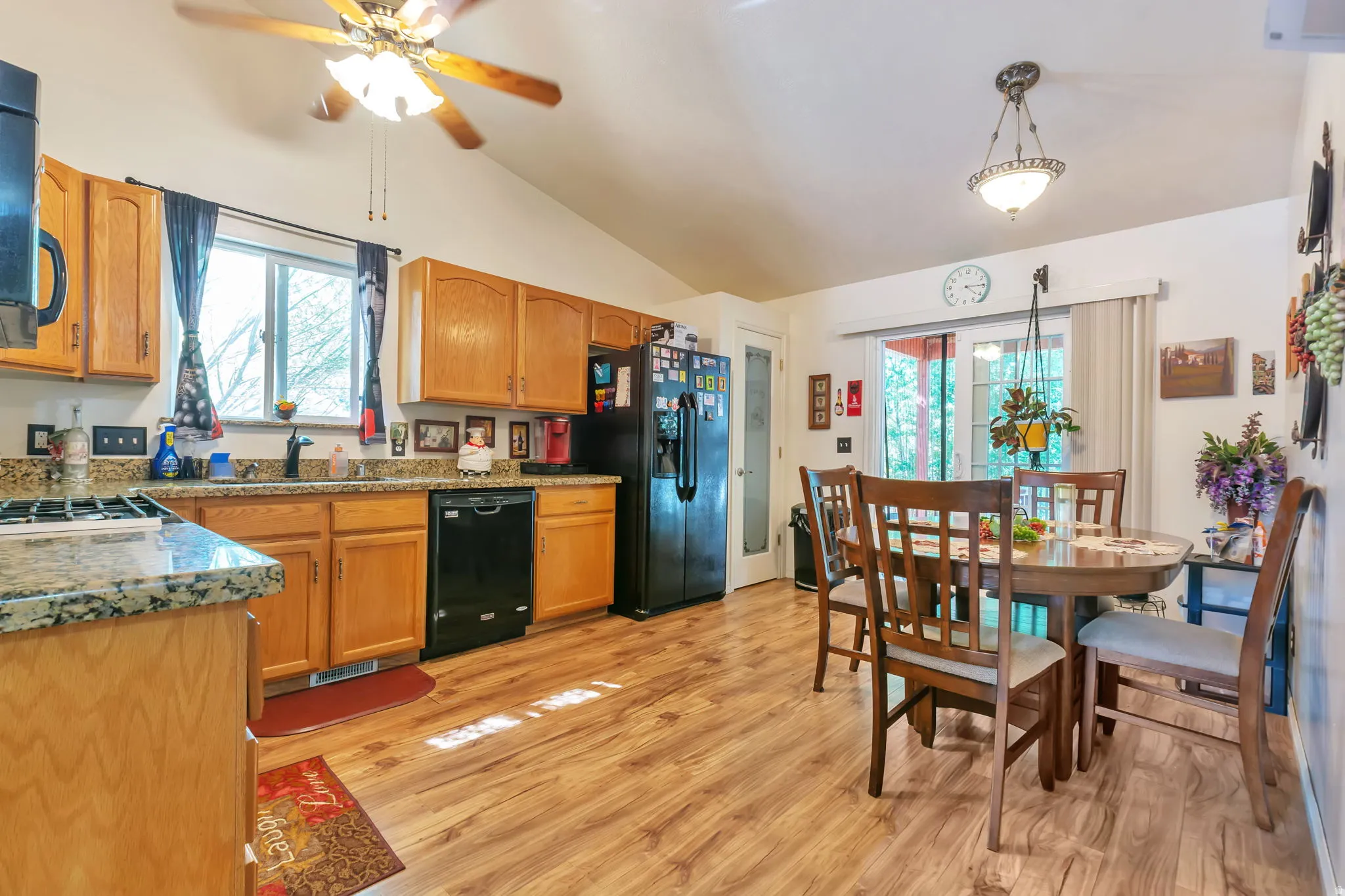 Kitchen featuring wood-finish flooring, vaulted ceiling with a ceiling fan, and light wood cabinetry