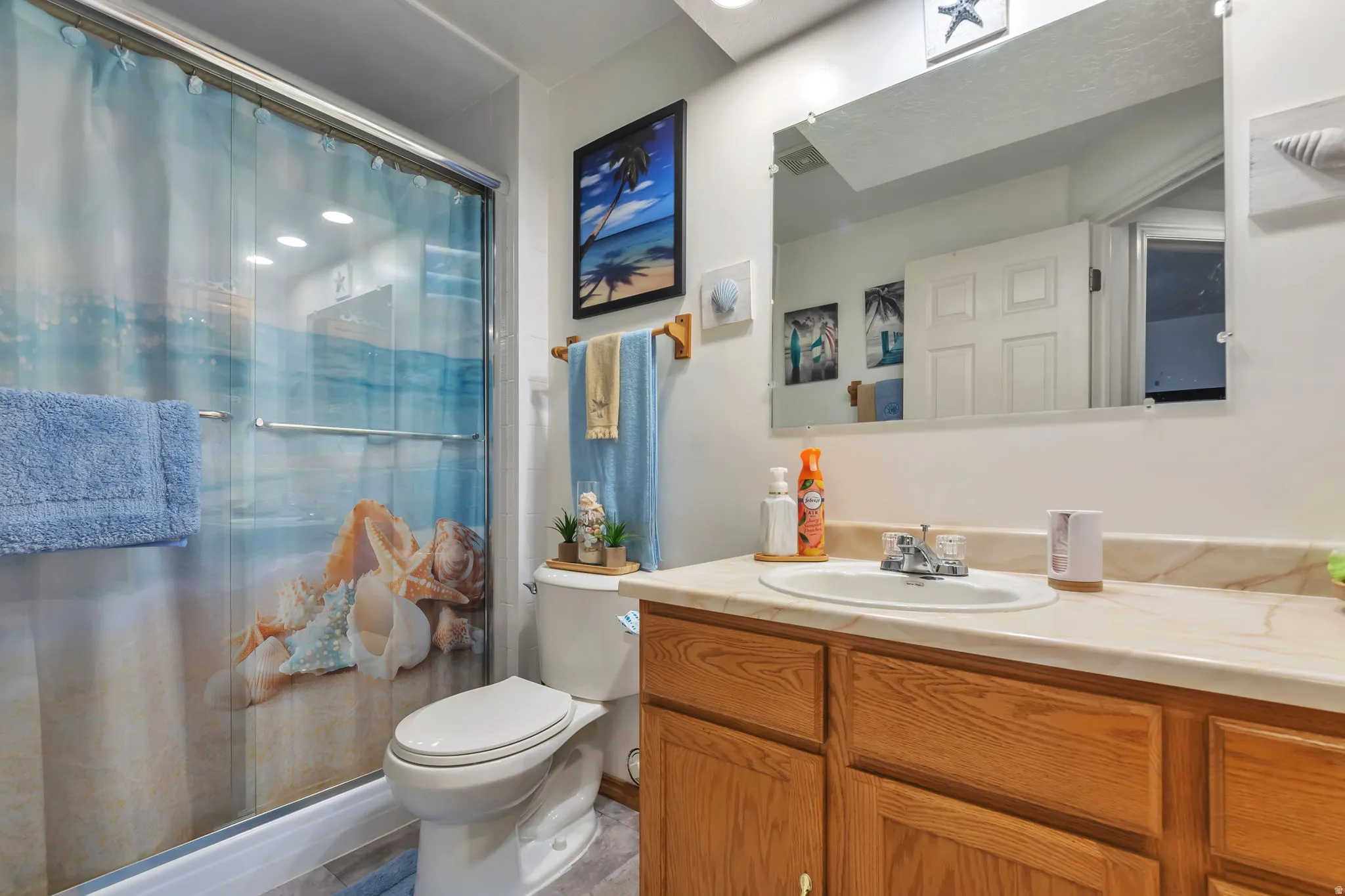 Full bathroom featuring a shower enclosure with sliding glass doors, a white toilet, and a wood-finish vanity with an integrated sink and light-colored countertop