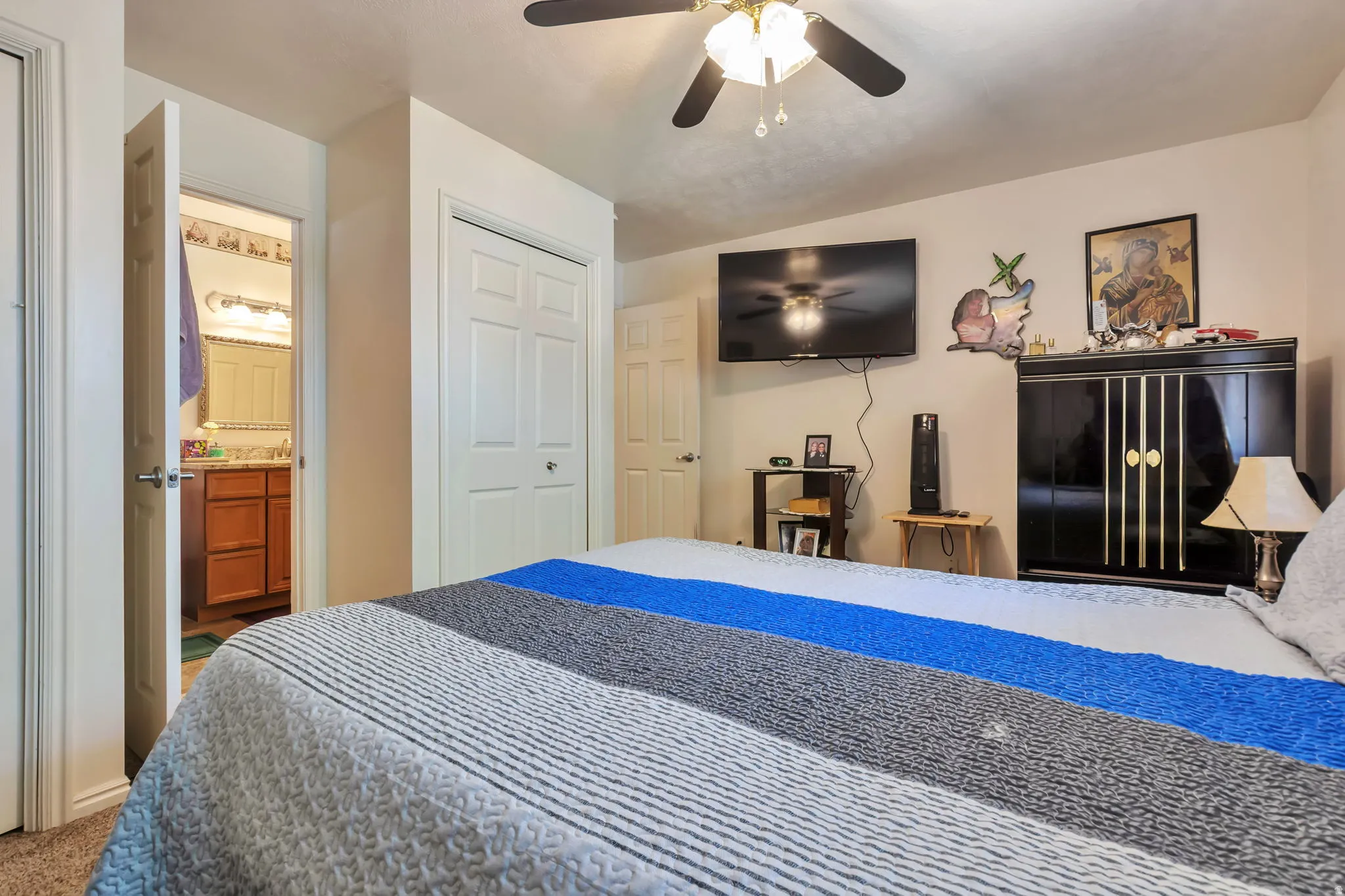 Bedroom featuring a ceiling fan with integrated lighting, wood-finish flooring, and a wall-mounted television