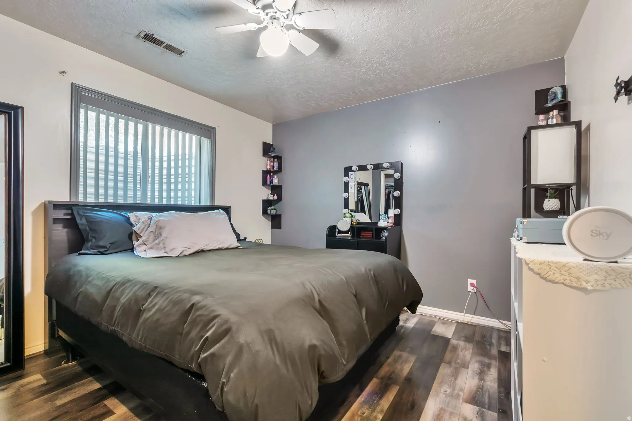 Spacious room featuring wood-finish flooring, a ceiling fan with integrated lighting, and a large window with horizontal blinds