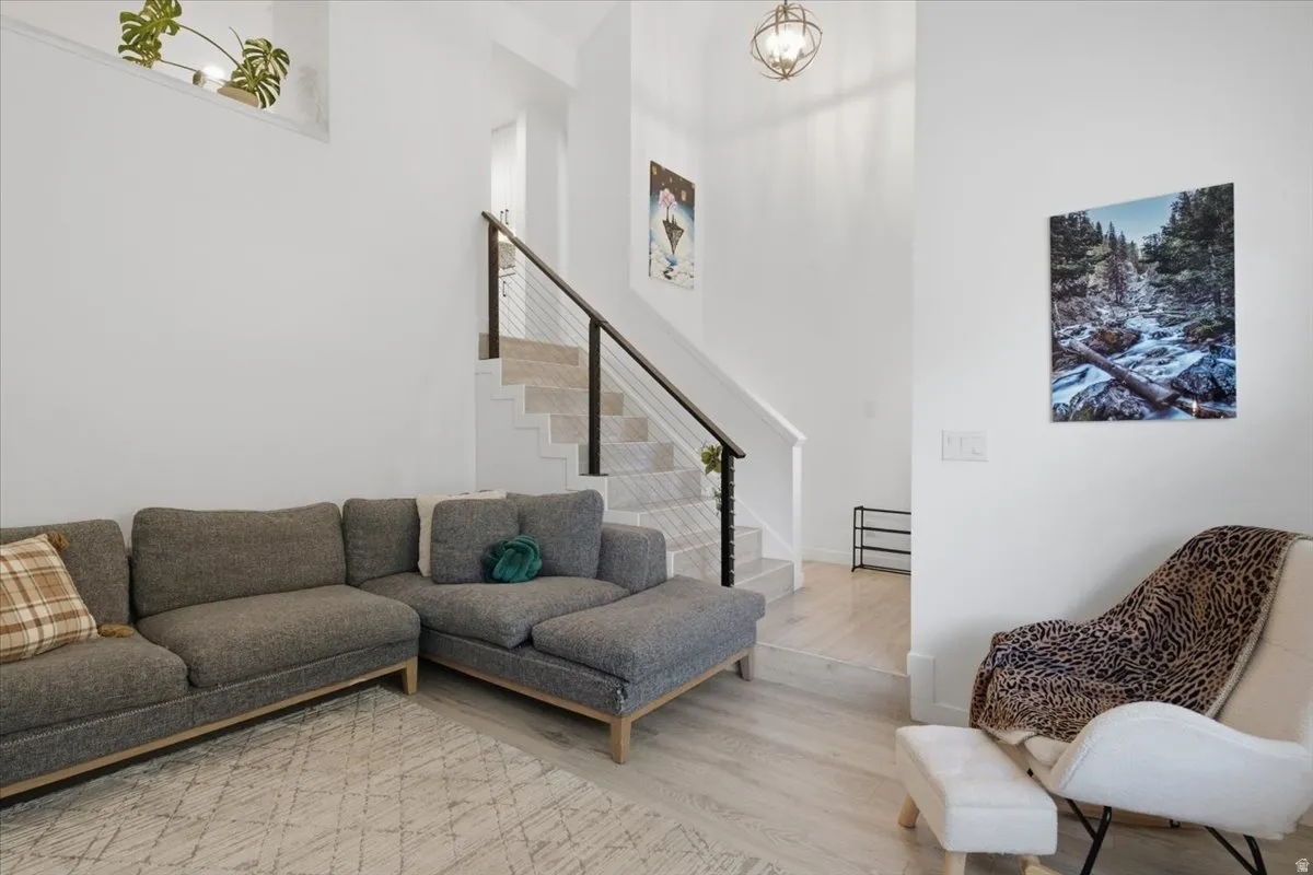 Bright interior featuring light wood-finish flooring and a staircase with black railings and cable balusters