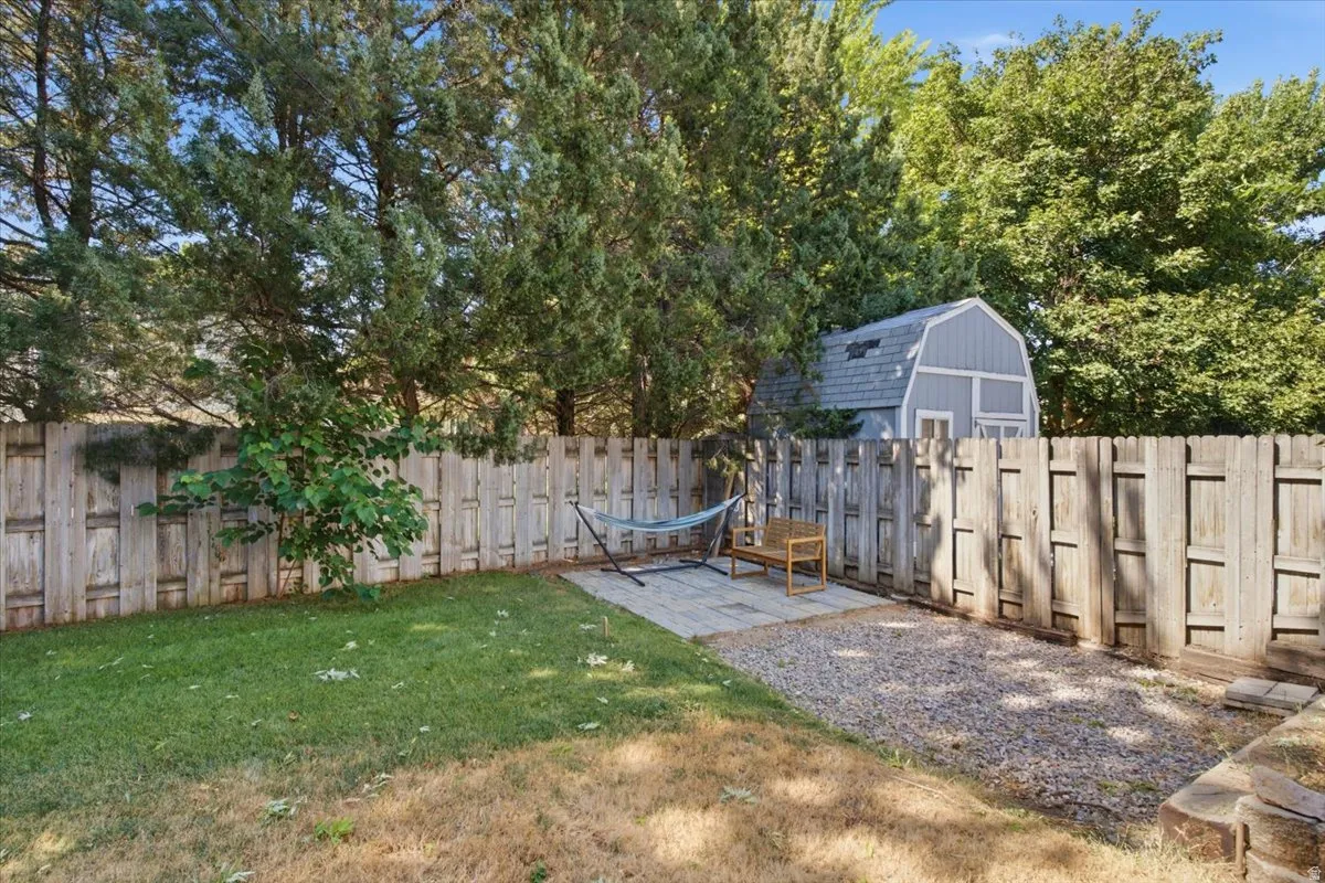 Private backyard featuring a wood privacy fence, a storage shed with a gambrel roof, and mature trees providing natural screening