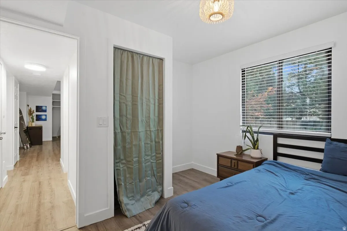 Bedroom featuring wood-finish flooring and a single window with horizontal blinds