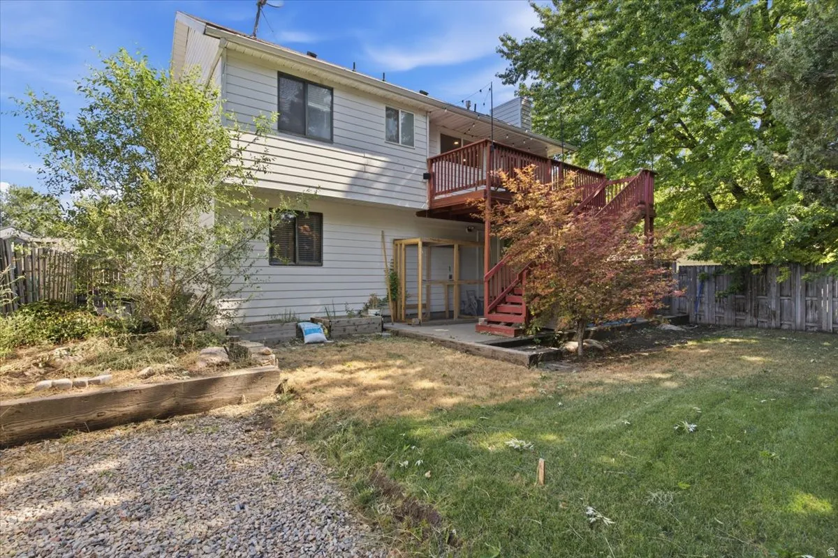 Rear exterior featuring wood siding, a multi-level wood deck, a ground-level concrete patio, and a mixed gravel and grass yard