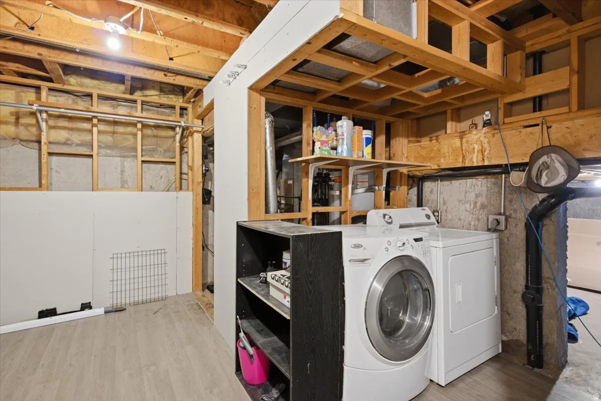 Utility area featuring wood-finish flooring, exposed ceiling joists, and partial drywall