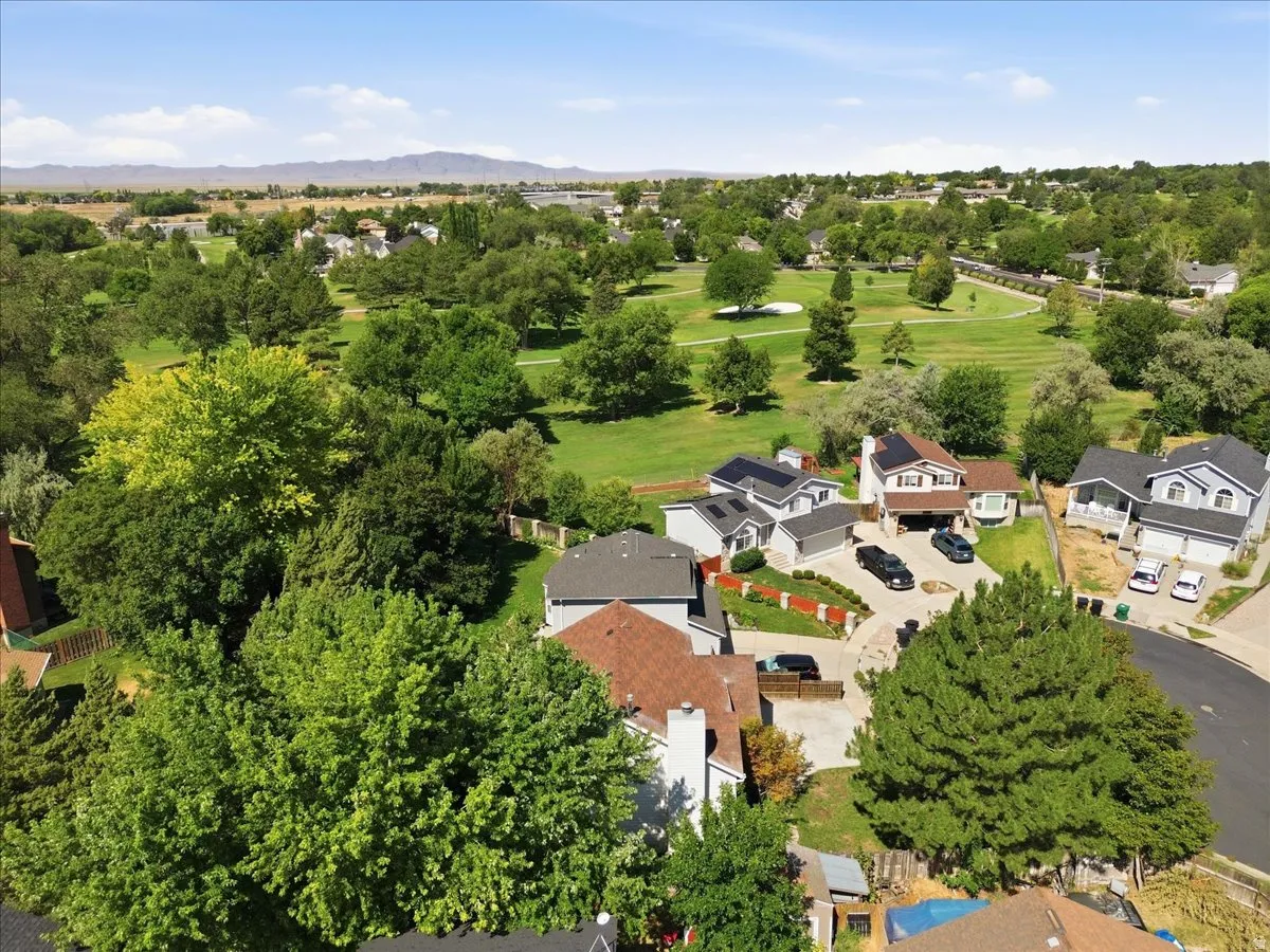 Aerial view showcasing residential properties surrounded by mature trees, expansive green spaces, and a golf course