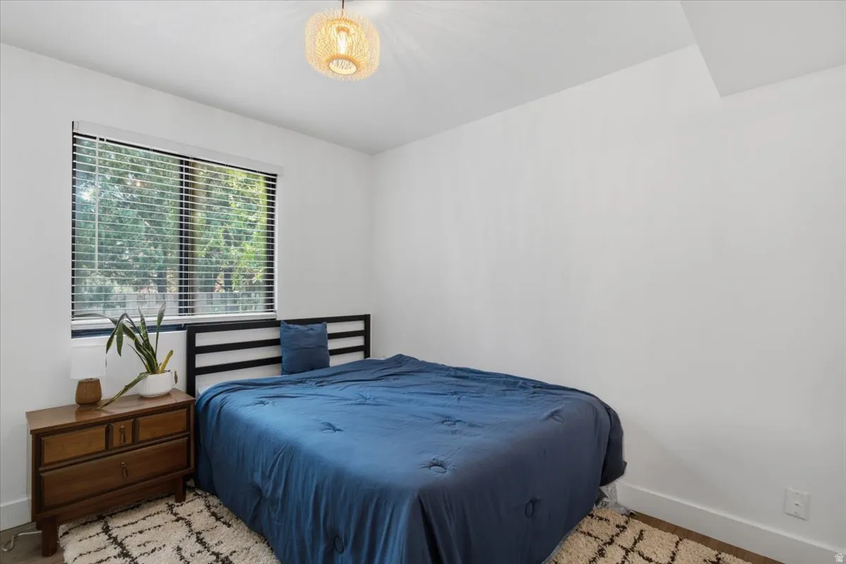 Bright room featuring a large window with blinds, a modern ceiling light fixture, and white wall finishes