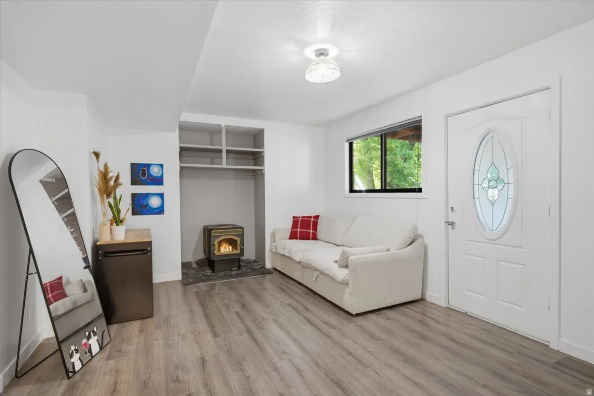 Spacious living area featuring wood-finish flooring, a decorative entry door with an oval stained-glass insert, and a built-in fireplace with a stone hearth