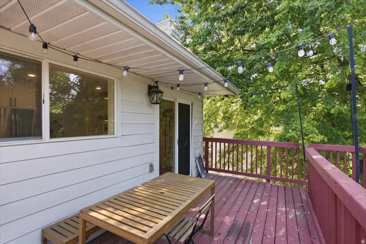 Deck featuring a red wood-finish railing and string lighting