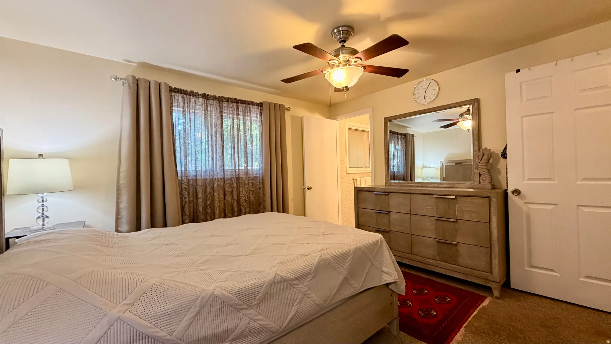 Spacious room featuring a ceiling fan with integrated lighting, a window with sheer and blackout drapery, and a neutral color palette