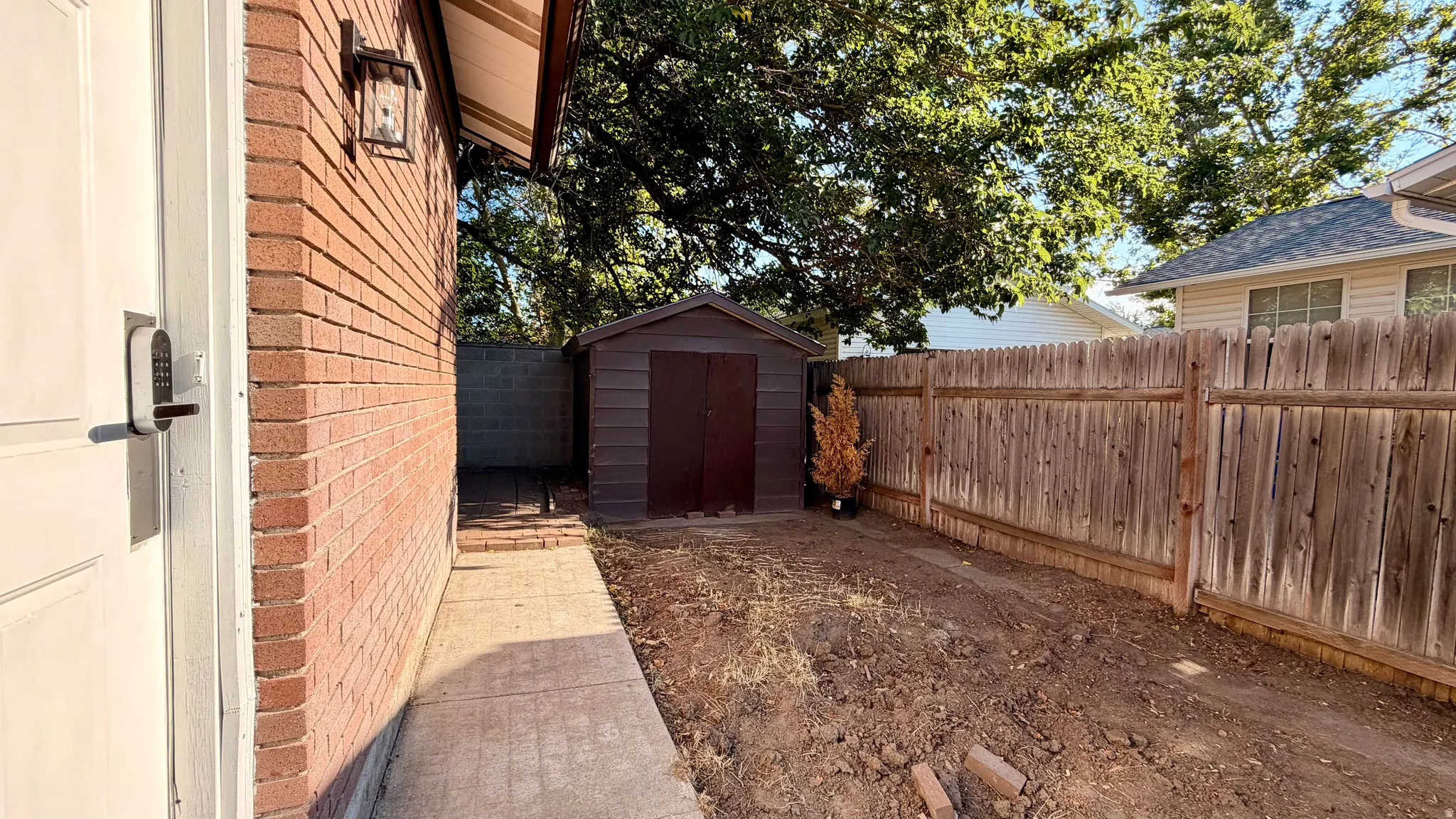 Side yard featuring a brick exterior wall, concrete walkway, and a privacy fence