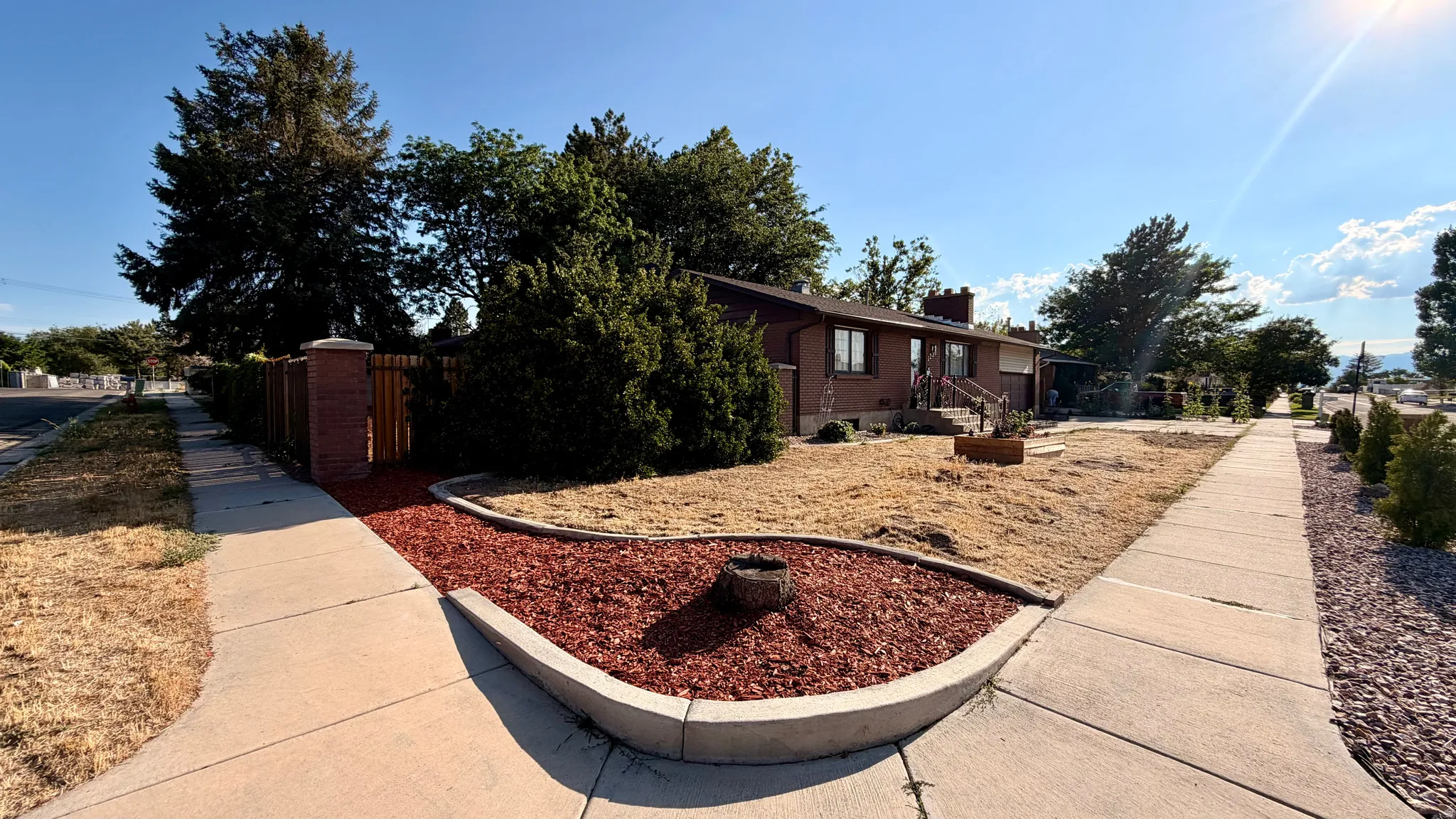 Brick exterior residence featuring a front yard, mature trees, and a concrete walkway