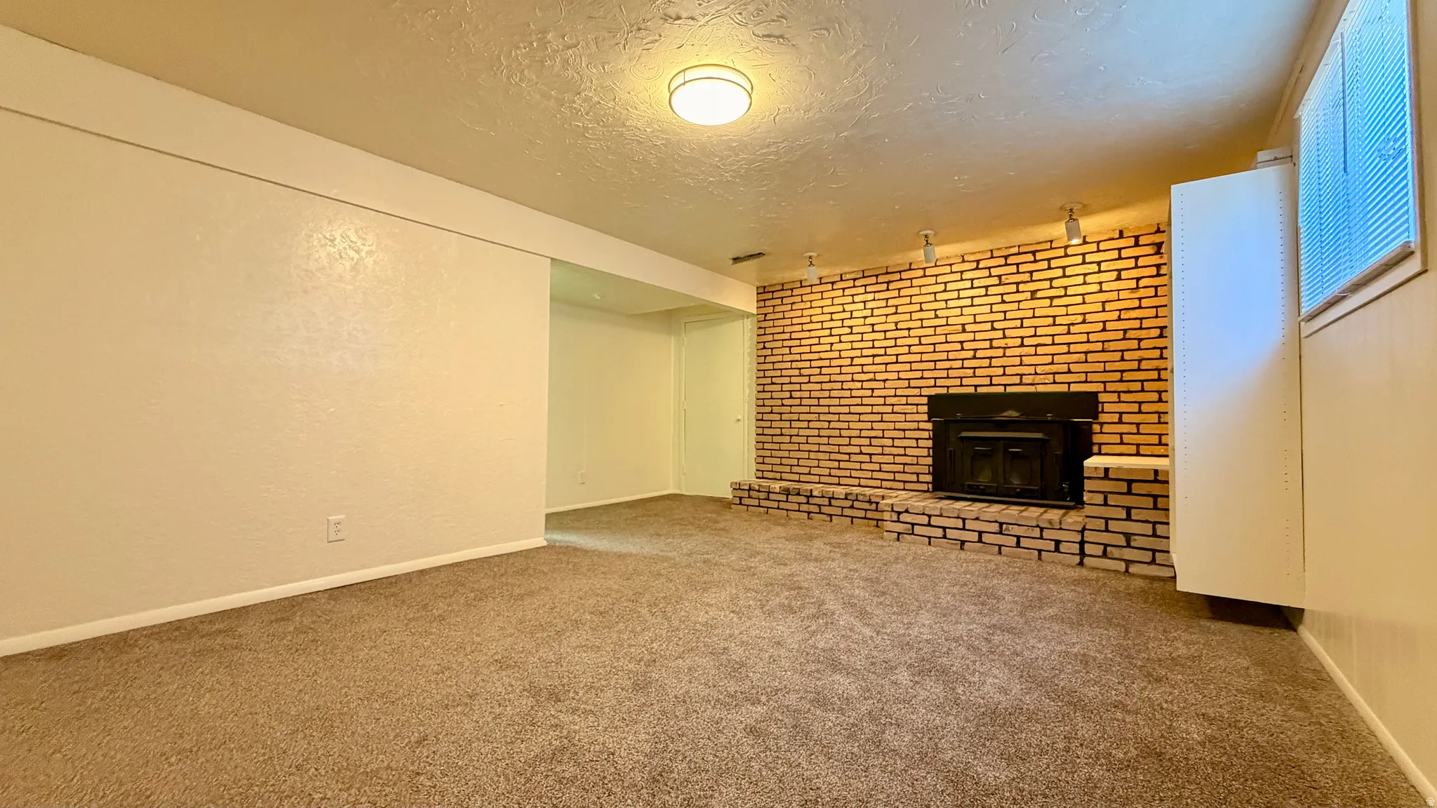 Brick fireplace with hearth, recessed metal fireplace insert, and track lighting