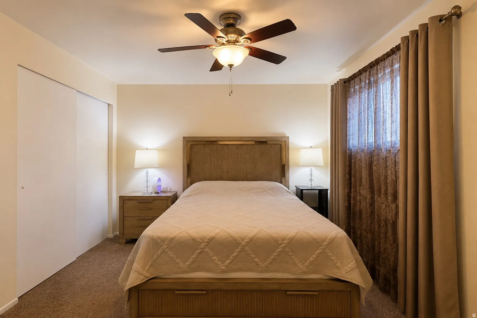 Bedroom featuring a ceiling fan with integrated lighting, wood-finish headboard, and sliding closet doors