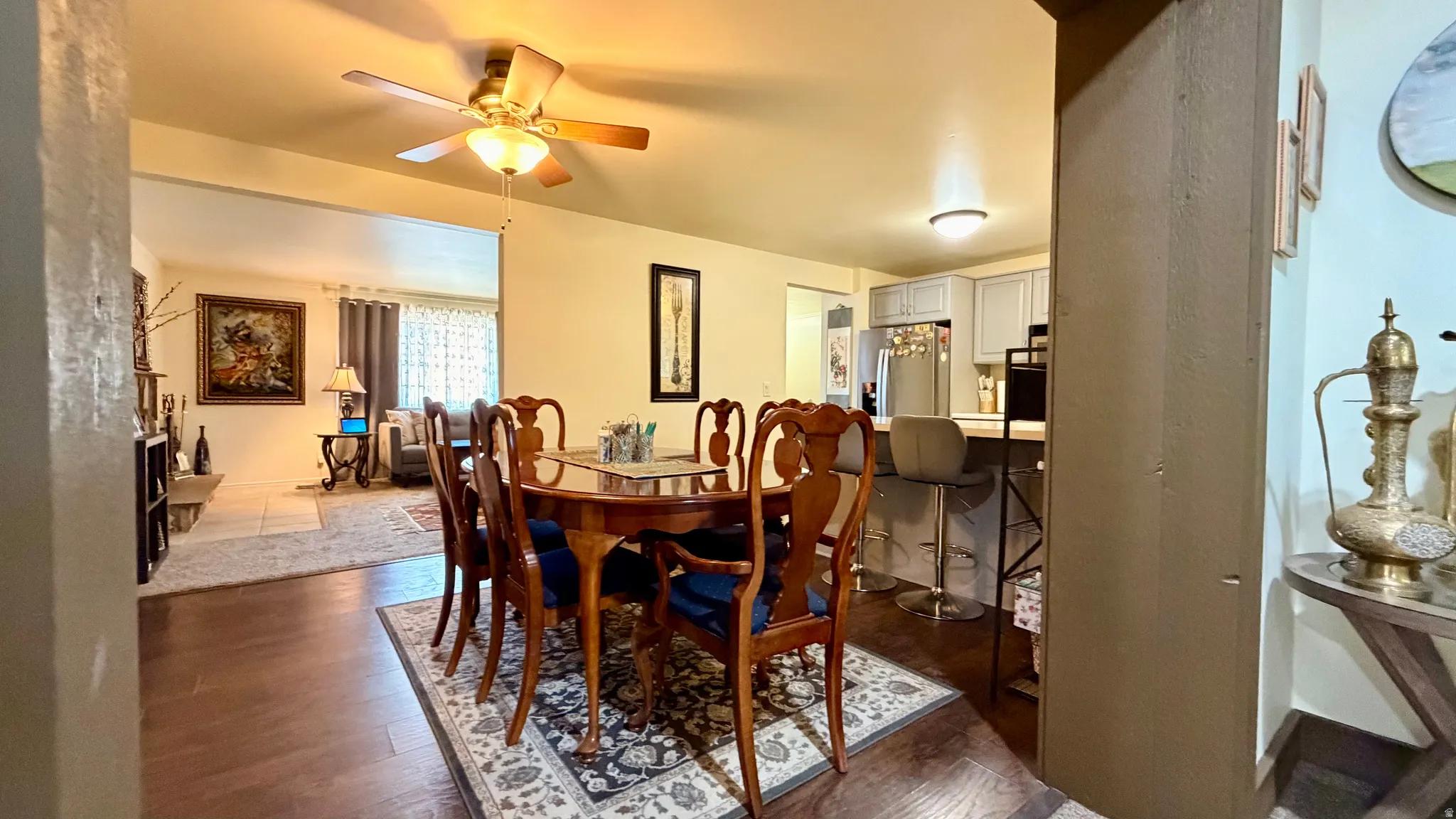 Spacious dining area featuring wood-finish flooring, a ceiling fan with integrated lighting, and an open concept layout connecting to additional living spaces