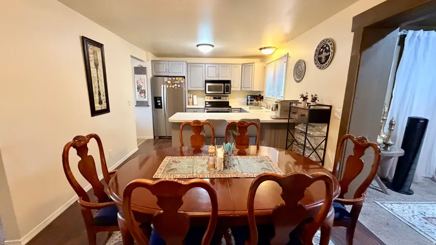 Dining area featuring wood-finish flooring, a neutral wall color, and an open concept layout with sightlines into the kitchen