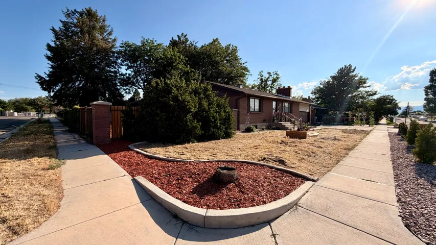 Brick exterior residence featuring a front yard, mature trees, and a concrete walkway