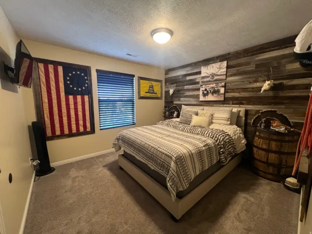 Bedroom featuring a wood-panel accent wall and neutral carpet flooring