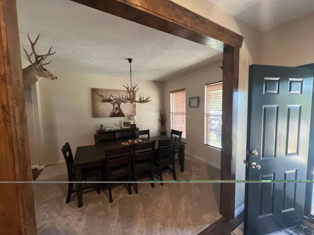 Entryway featuring a paneled door and wood-finish trim opening to a carpeted room with multiple windows