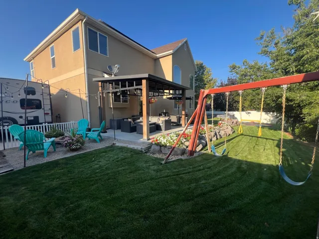 Expansive backyard featuring a lush lawn, mature landscaping, and a covered patio structure