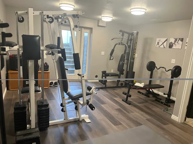 Versatile recreation room featuring wood-finish flooring, recessed lighting, and a glass-paneled double door for outdoor access