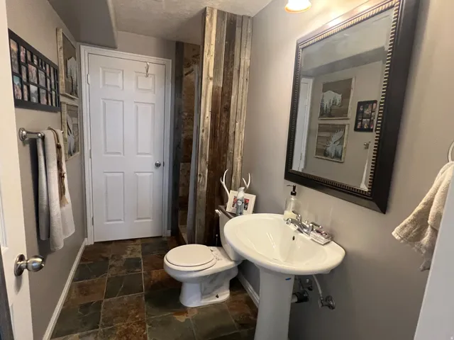 Bathroom featuring a pedestal sink, framed mirror, and slate-finish floor tile
