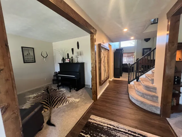 Expansive foyer featuring wood-finish flooring, a carpeted curved staircase with dark iron balusters, and recessed lighting