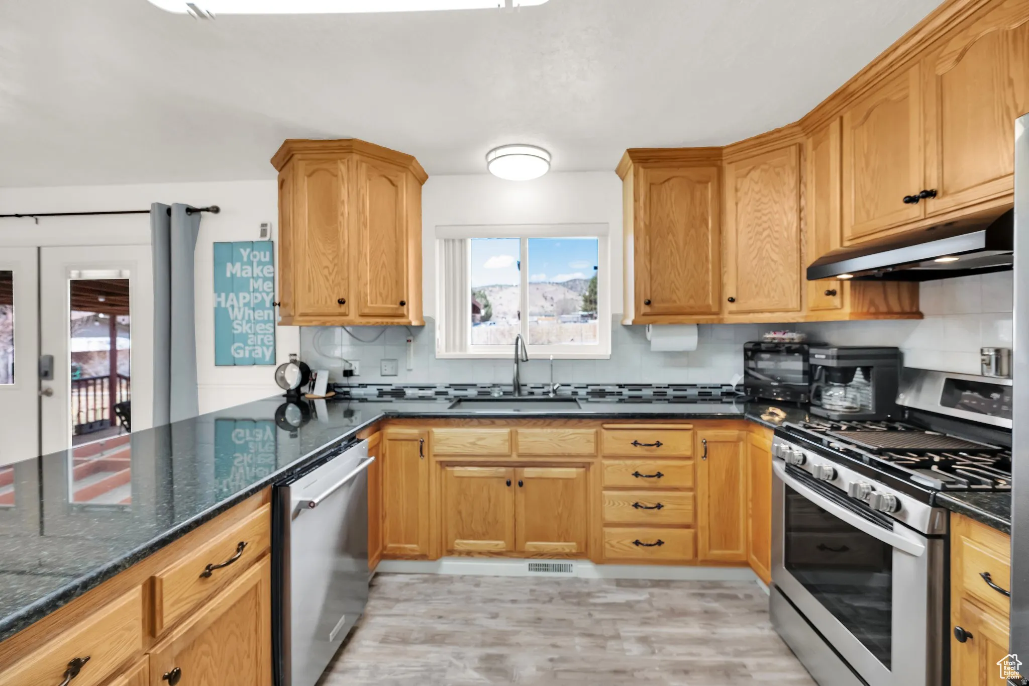 Kitchen featuring abundant wood cabinetry, dark countertops, stainless steel appliances, and a tile backsplash