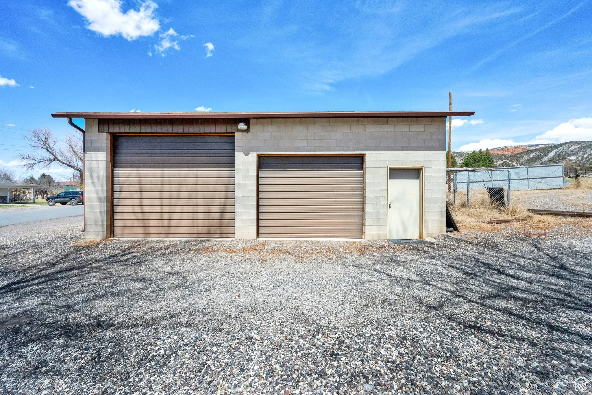 Concrete block outbuilding featuring two roll-up garage doors and a pedestrian entry door