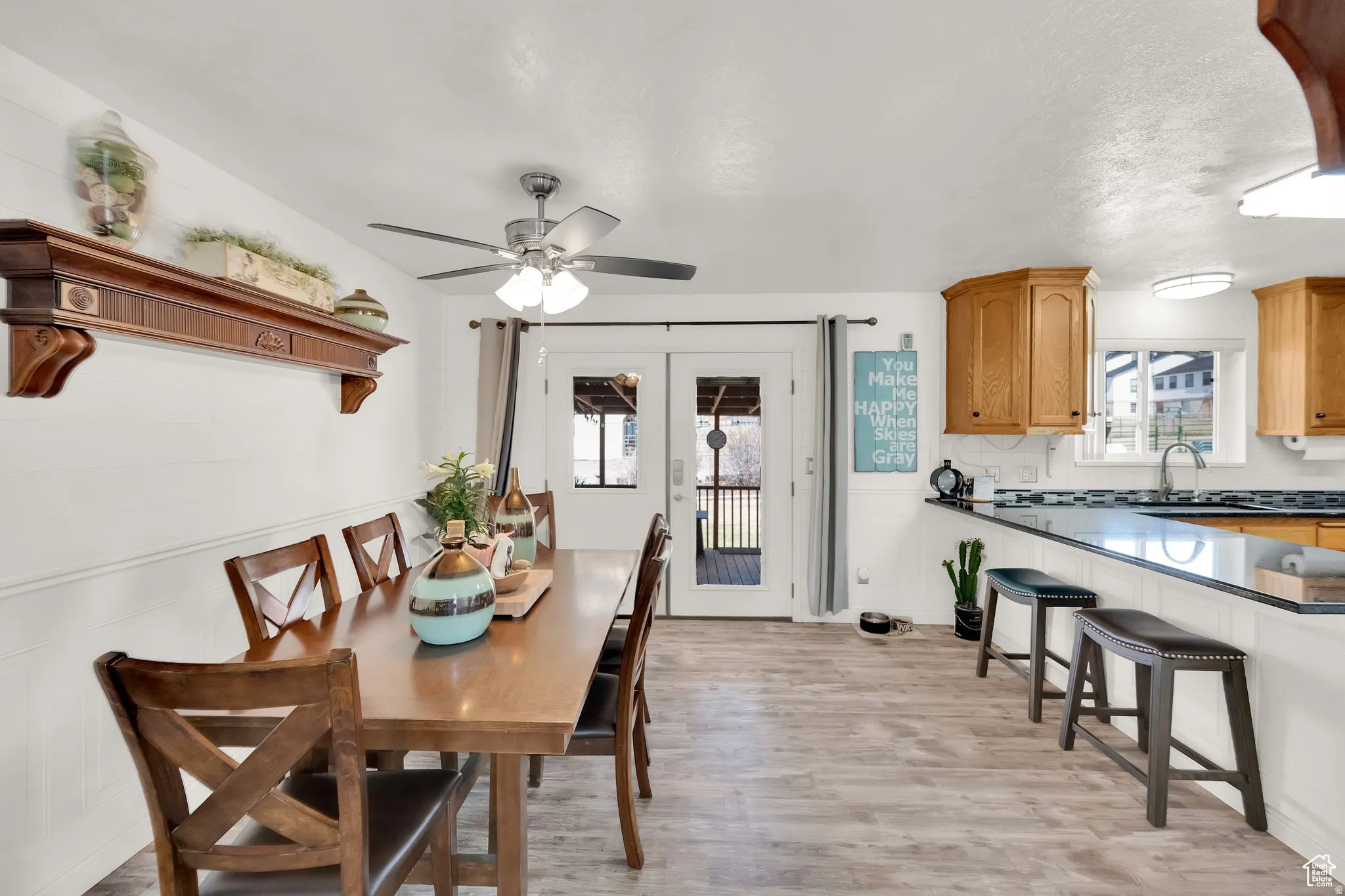 Dining area with wood-finish flooring, white wainscoting, and a ceiling fan with integrated lighting