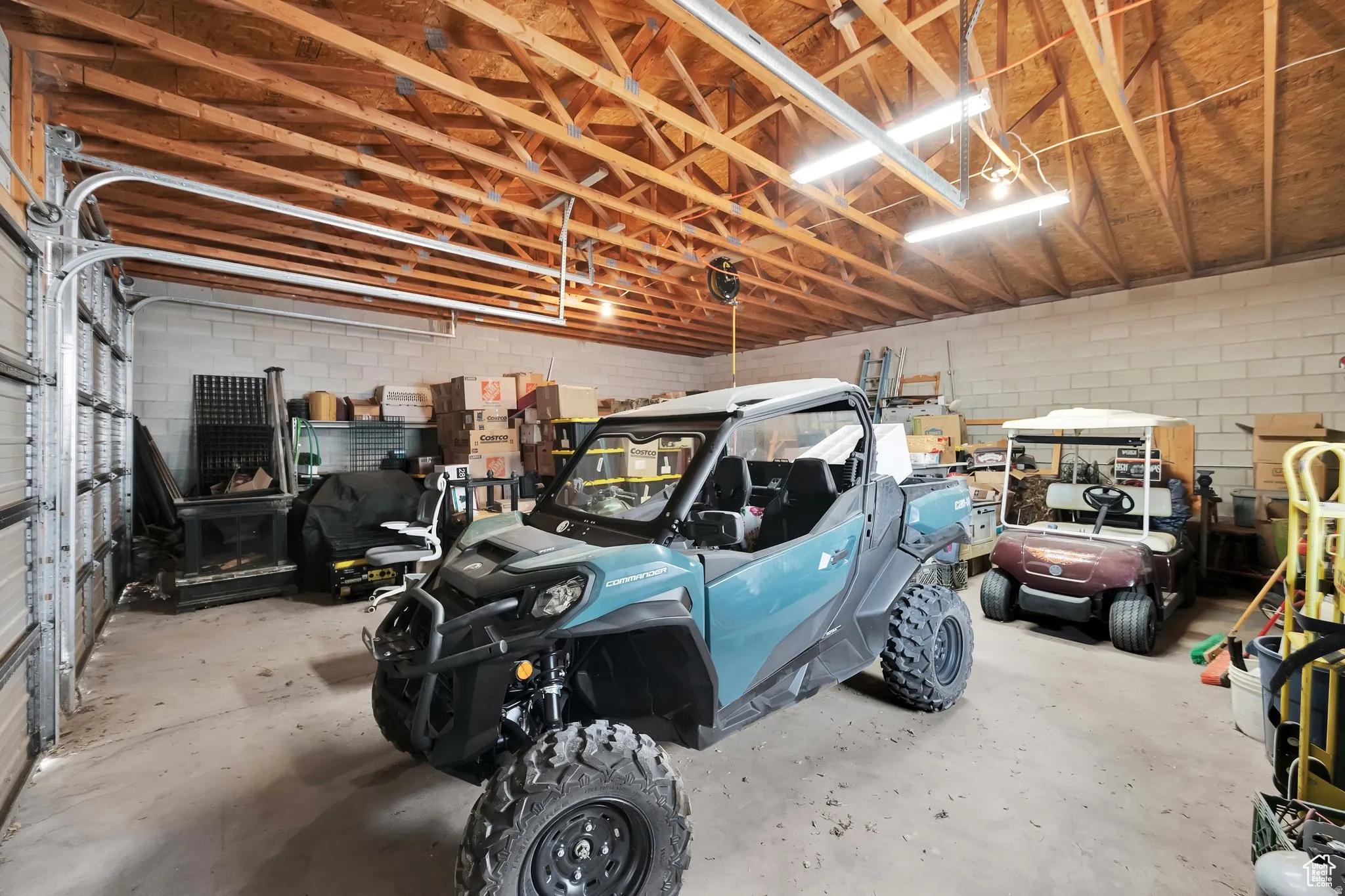Spacious garage with exposed wood ceiling trusses, concrete block walls, and concrete flooring