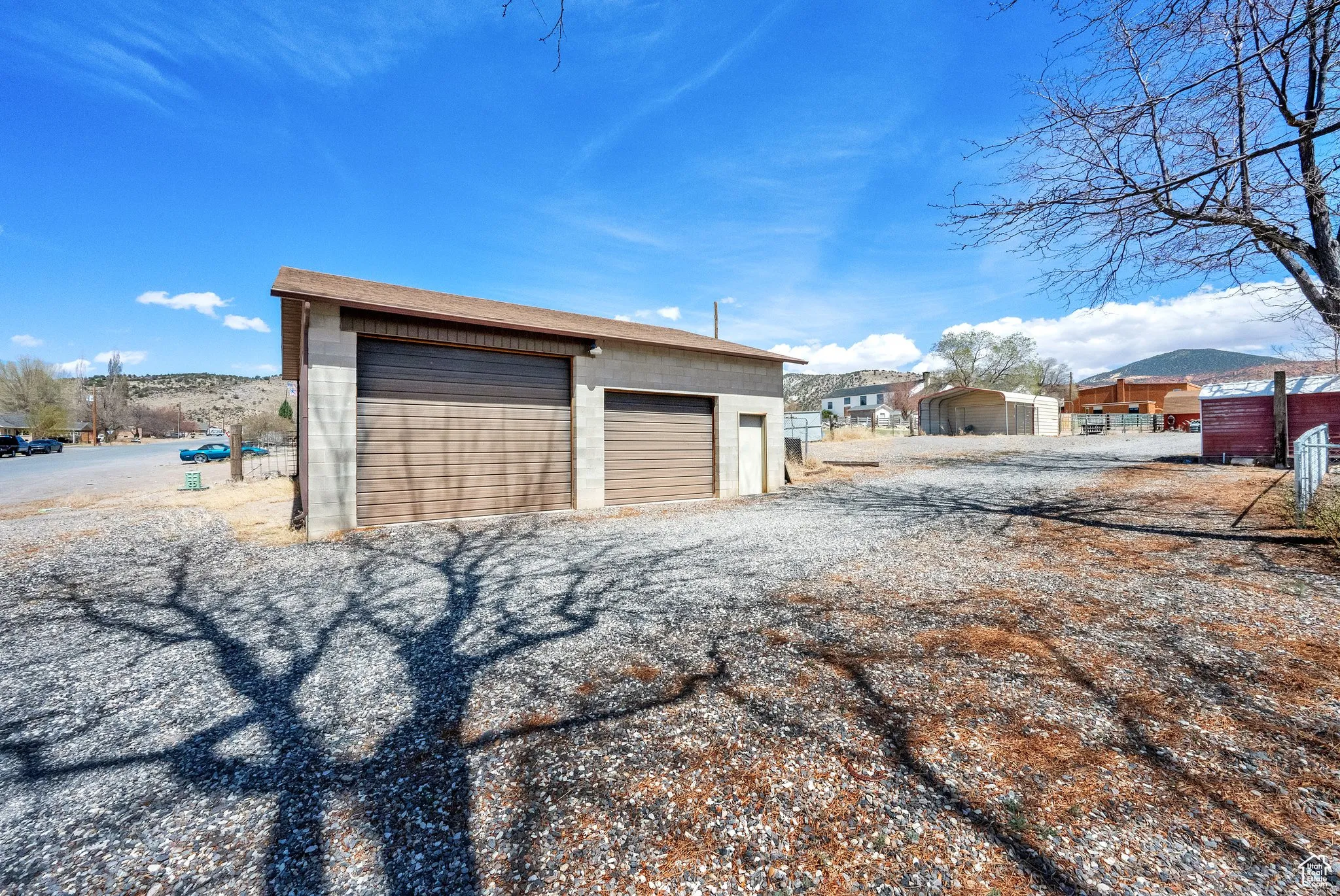 Detached garage featuring two overhead doors, a sloped roofline, and gravel surfacing