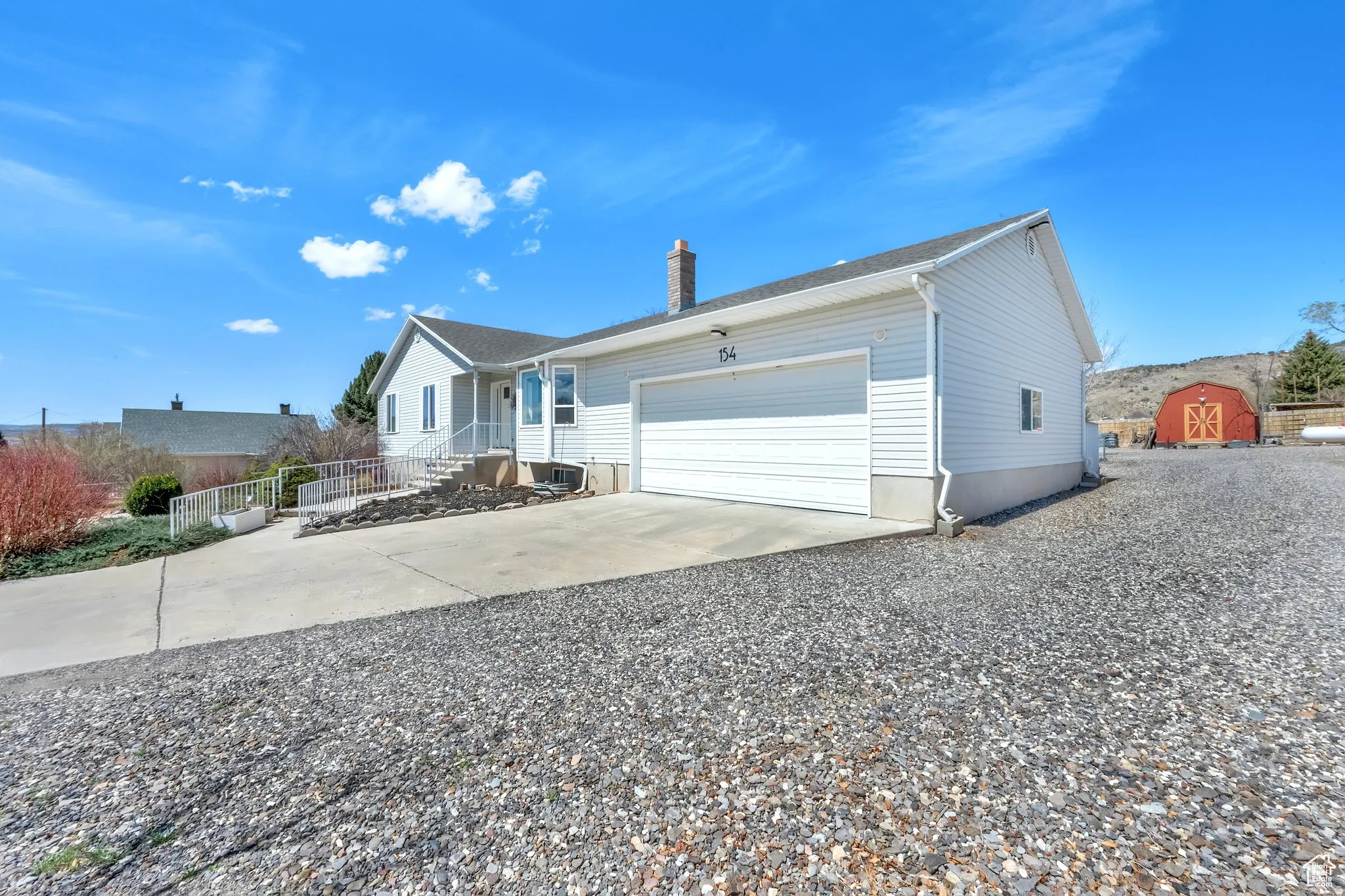 Ranch-style residence featuring light-colored siding, an attached garage, a concrete driveway, and a red outbuilding