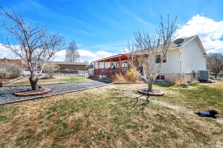 Exterior featuring white siding, a covered deck with red railings, and a gravel pathway