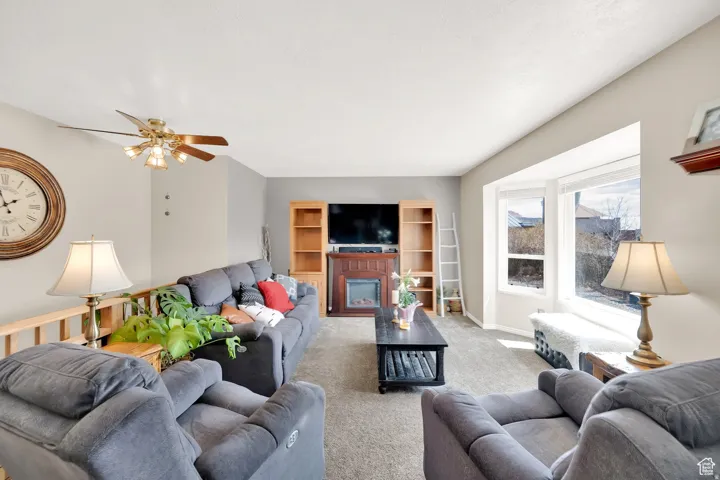 Living room featuring a bay window, ceiling fan, and carpeted flooring
