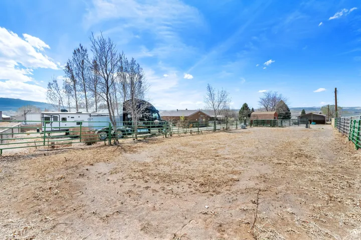 Expansive fenced outdoor area featuring a combination of wood and green metal fencing