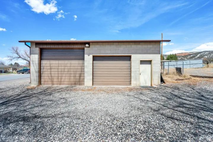 Concrete block outbuilding featuring two roll-up garage doors and a pedestrian entry door