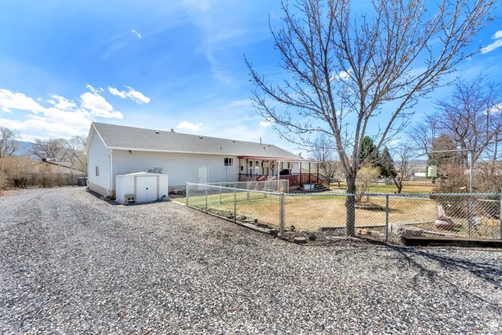 Spacious gravel driveway with a chain-link fence enclosing a backyard area