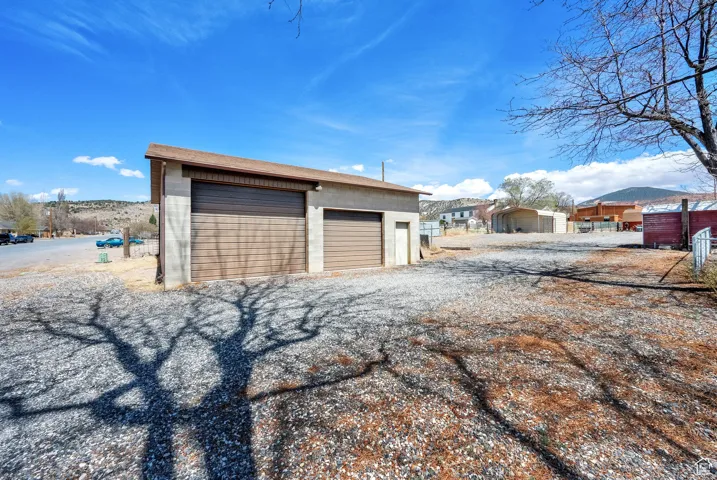 Detached garage featuring two overhead doors, a sloped roofline, and gravel surfacing