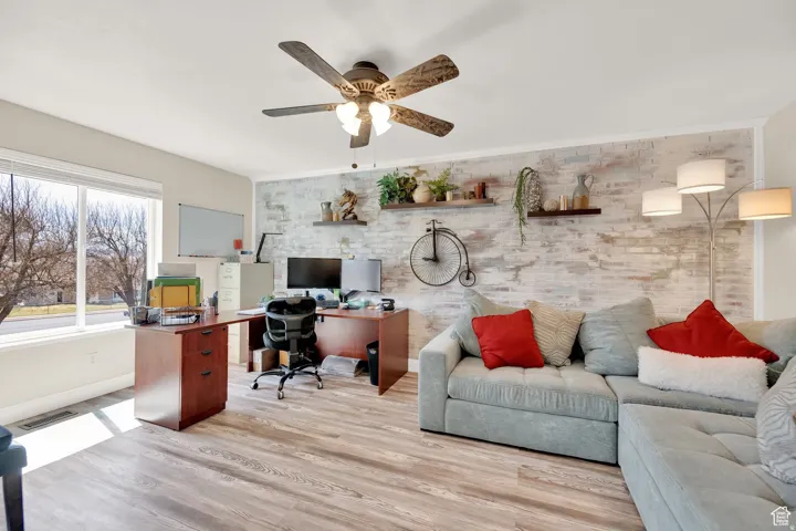 Bright interior space featuring wood-finish flooring and a whitewashed brick accent wall
