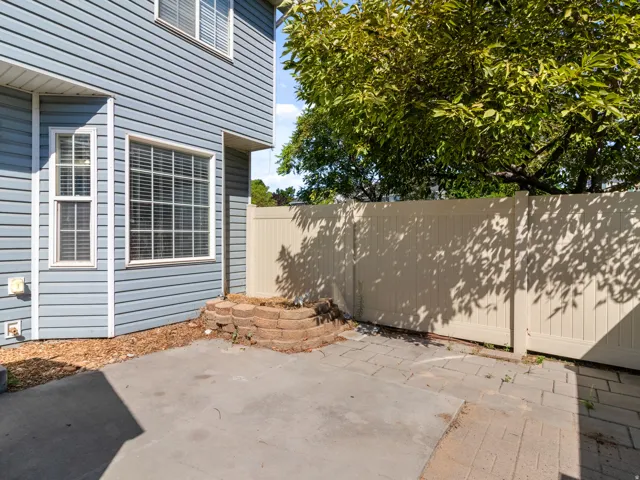 Paved patio area, privacy fencing, blue siding, and mature landscaping