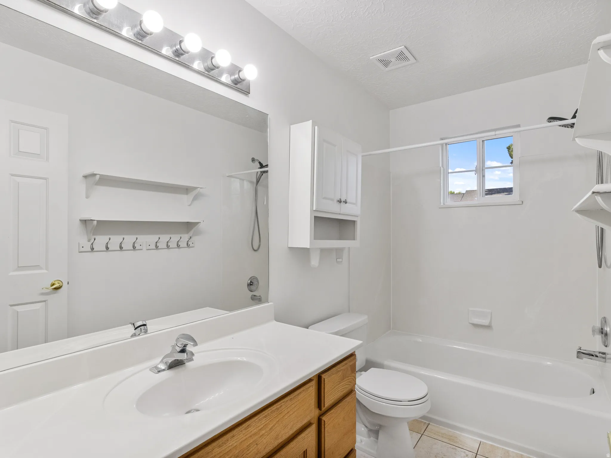 Bright and functional bathroom featuring a wood-finish vanity with dual-sink configuration, white quartz countertop, and chrome fixtures