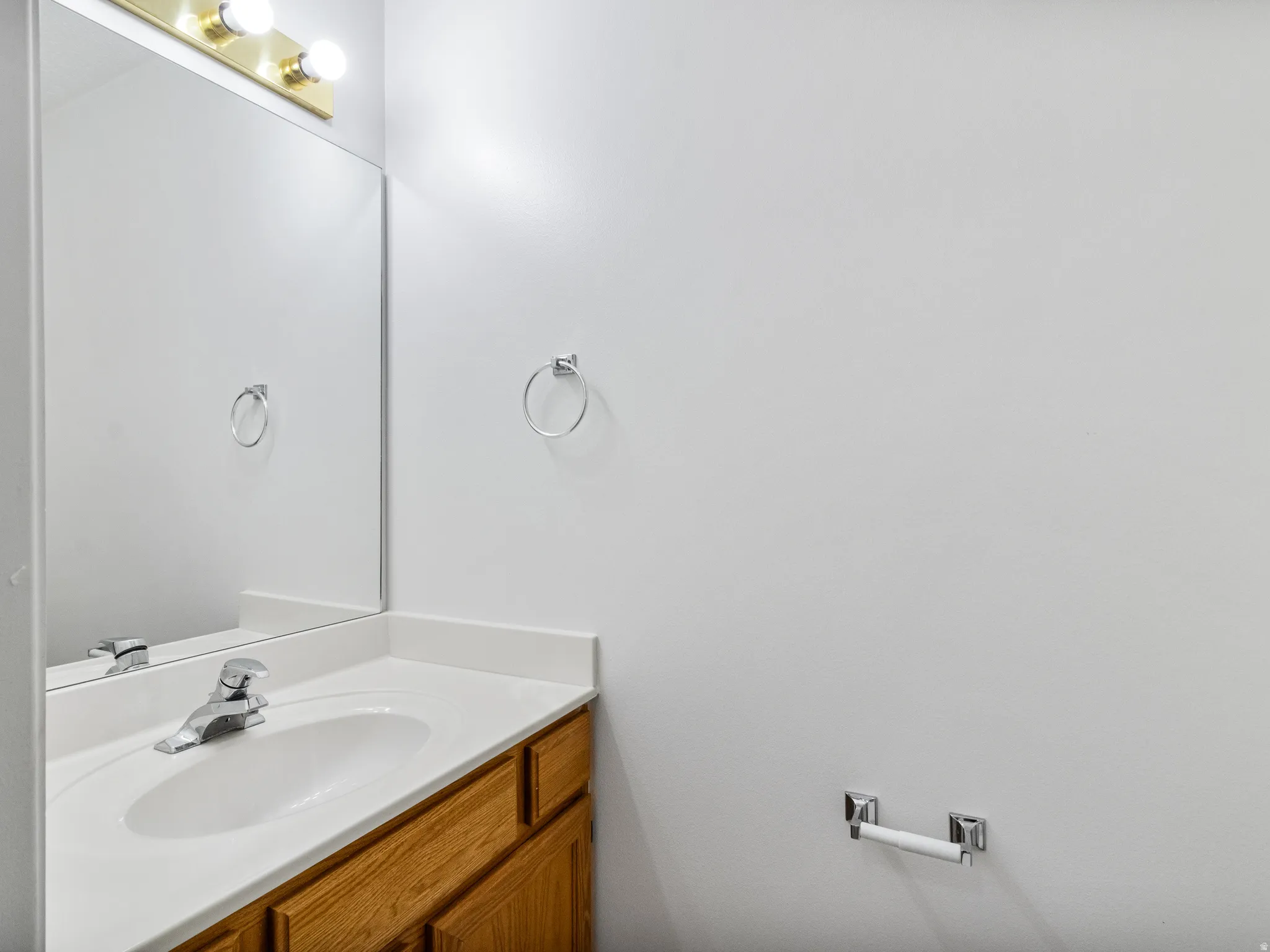 Bathroom vanity featuring wood-finish cabinetry, a white countertop with an integrated sink, and a chrome single-handle faucet