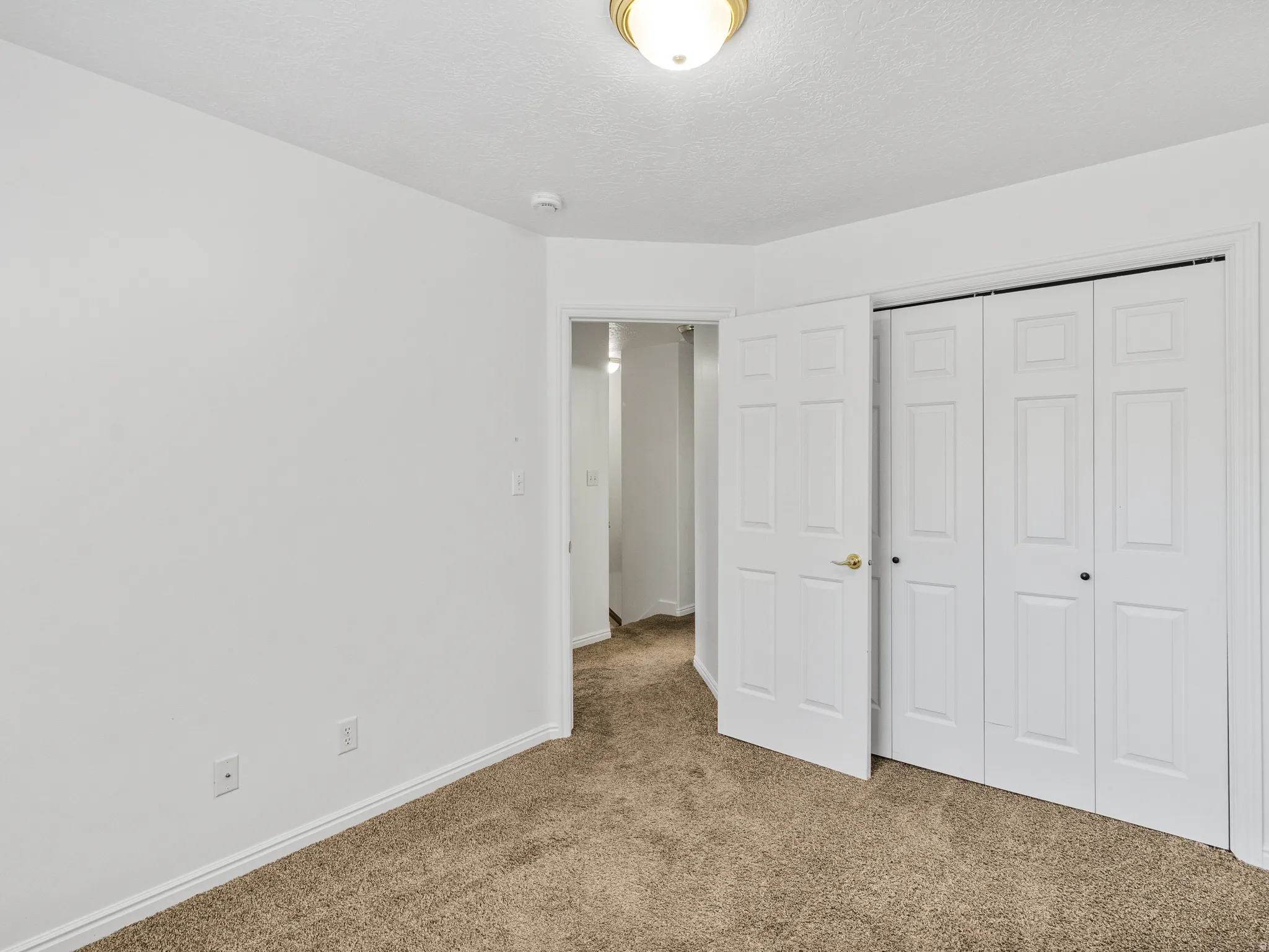 Interior room featuring light brown carpet flooring, white baseboards, and neutral white walls
