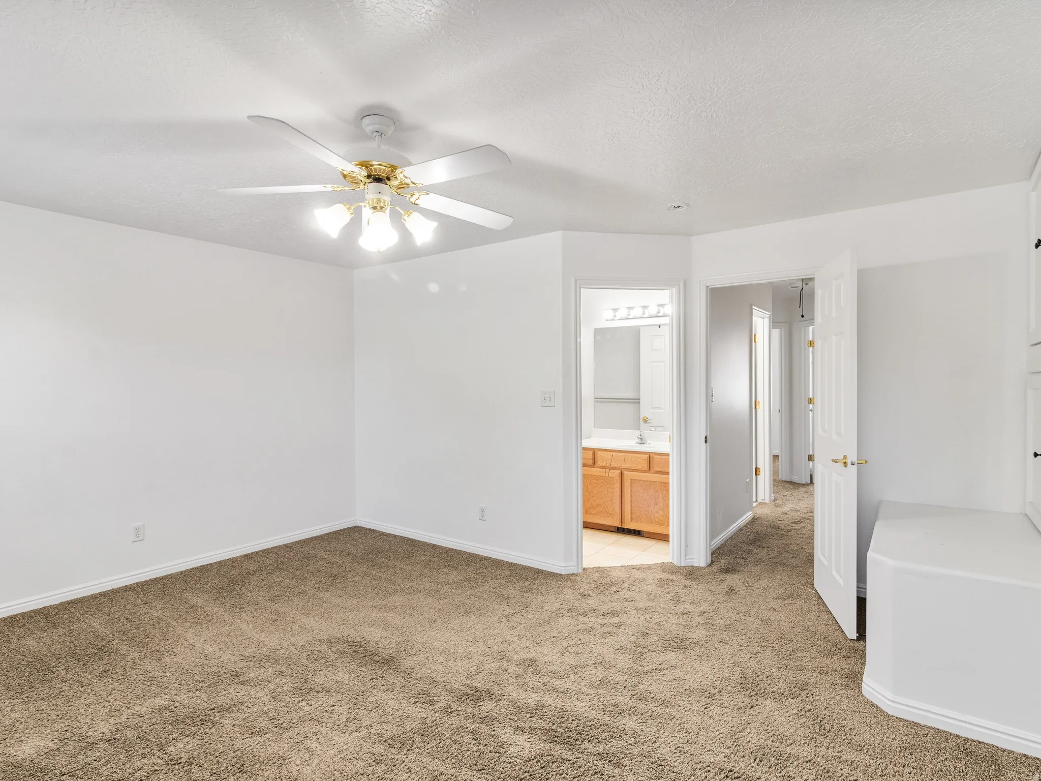 Spacious room featuring neutral carpeting, a ceiling fan with integrated lighting, and white walls
