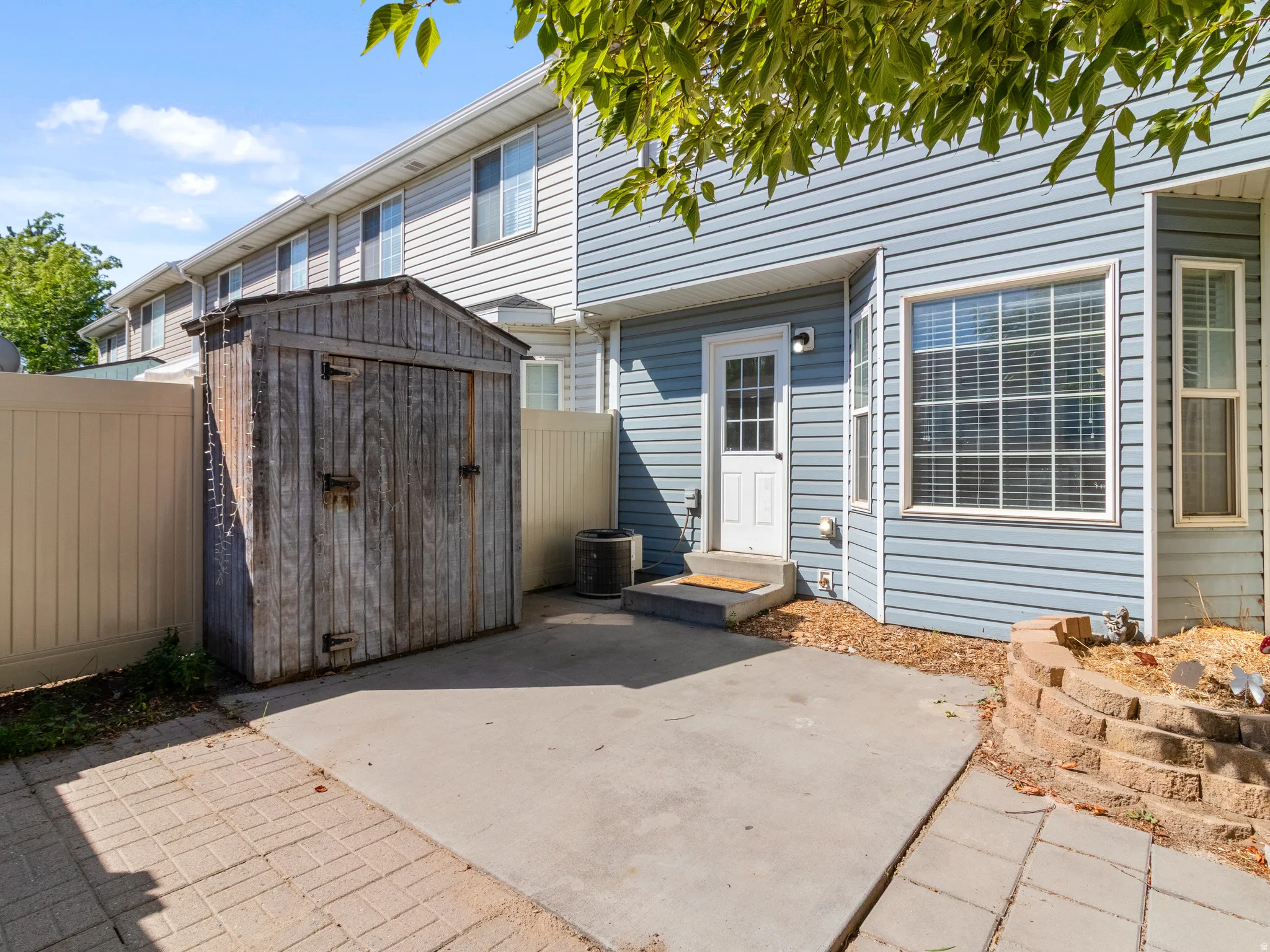 Private outdoor patio featuring a storage shed, concrete surface, and paver accents