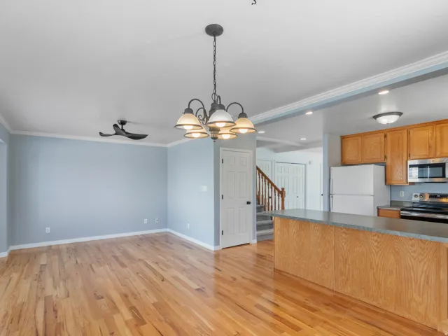Hardwood flooring throughout, crown molding, a ceiling fan, and a chandelier illuminate the space