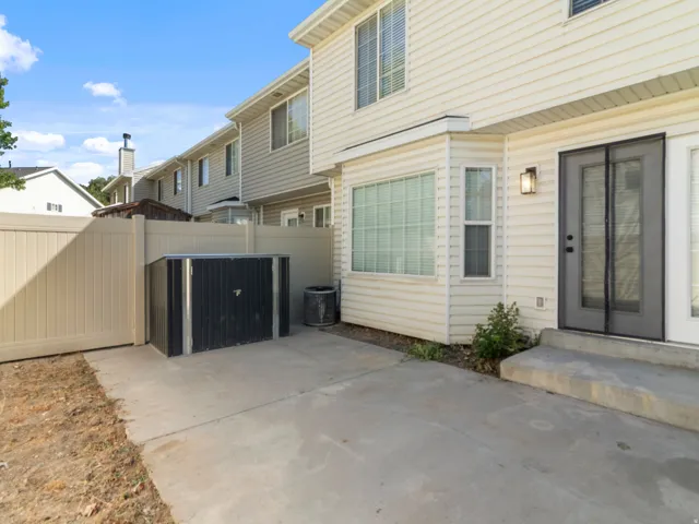 Concrete patio with a privacy fence, bay window, and exterior lighting fixture